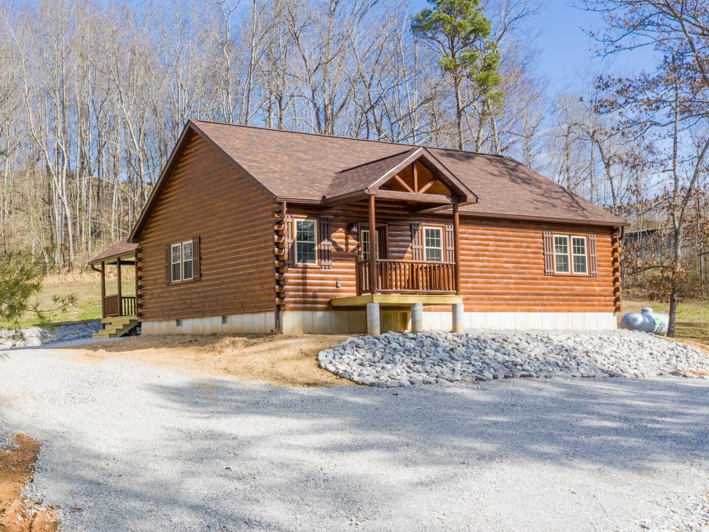 Sunset Ridge log cabin with full-length covered porch and decorative timber framing.