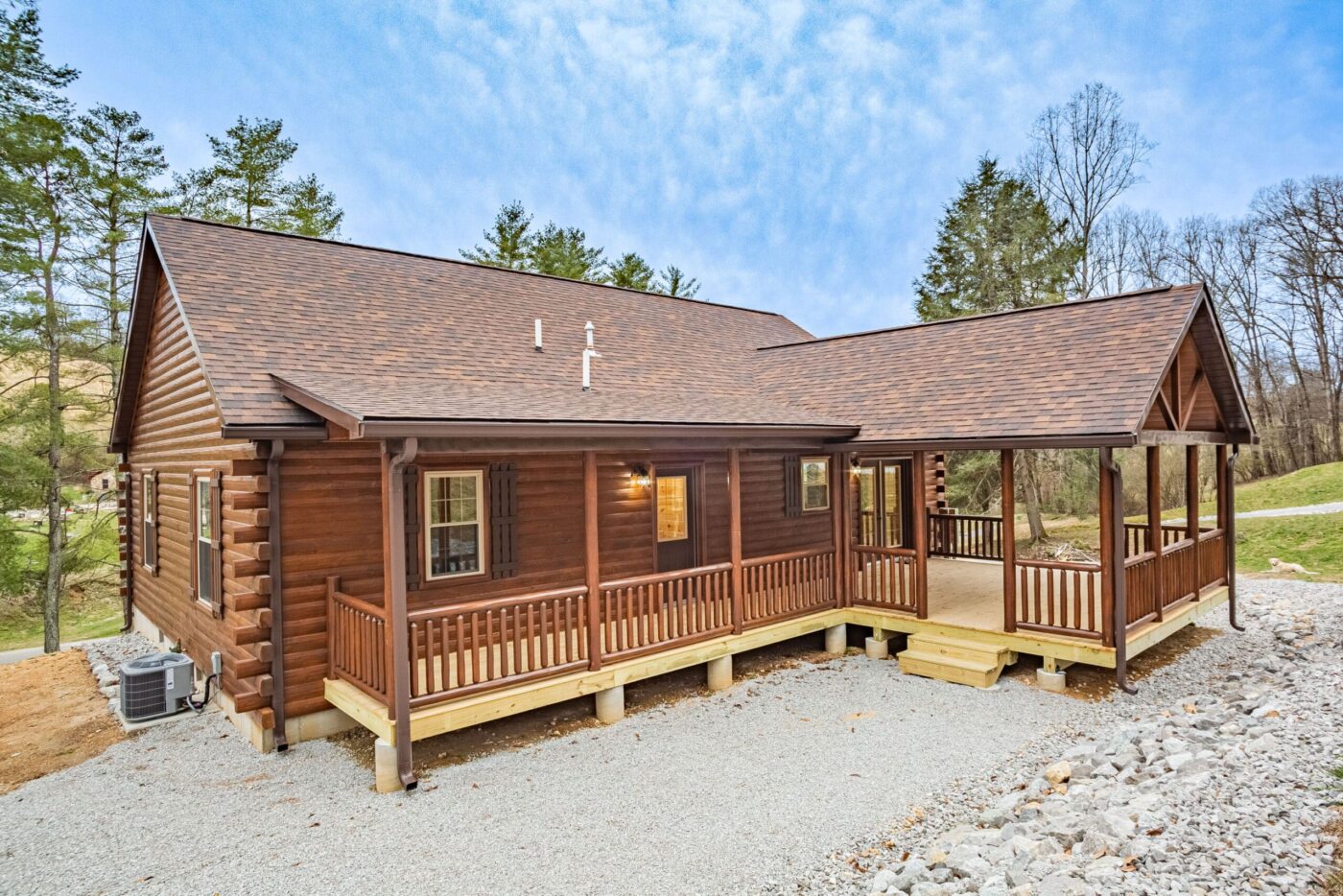 Sunset Ridge log cabin with green roof set against wooded hills in North Carolina.