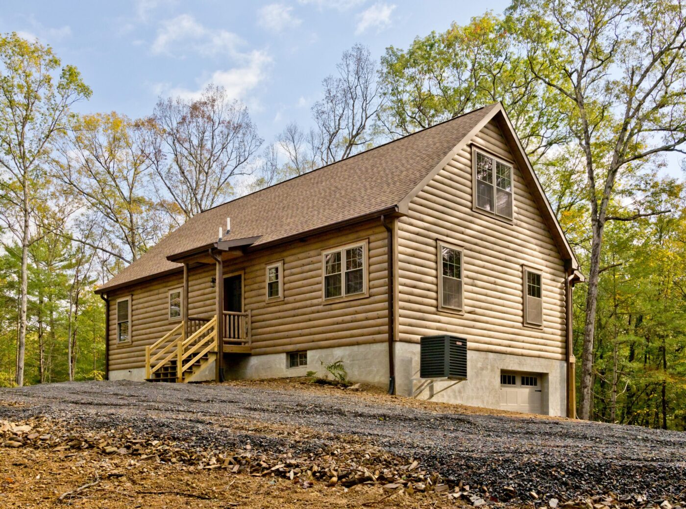 Sloped-roof log cabin with multiple windows set on a raised foundation in a wooded area.
