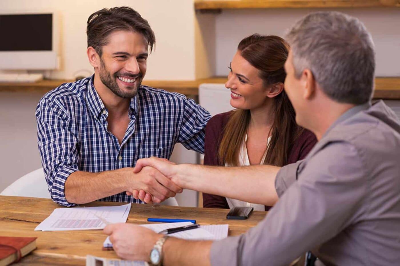 Family shaking hands with a lender over financing a log cabin