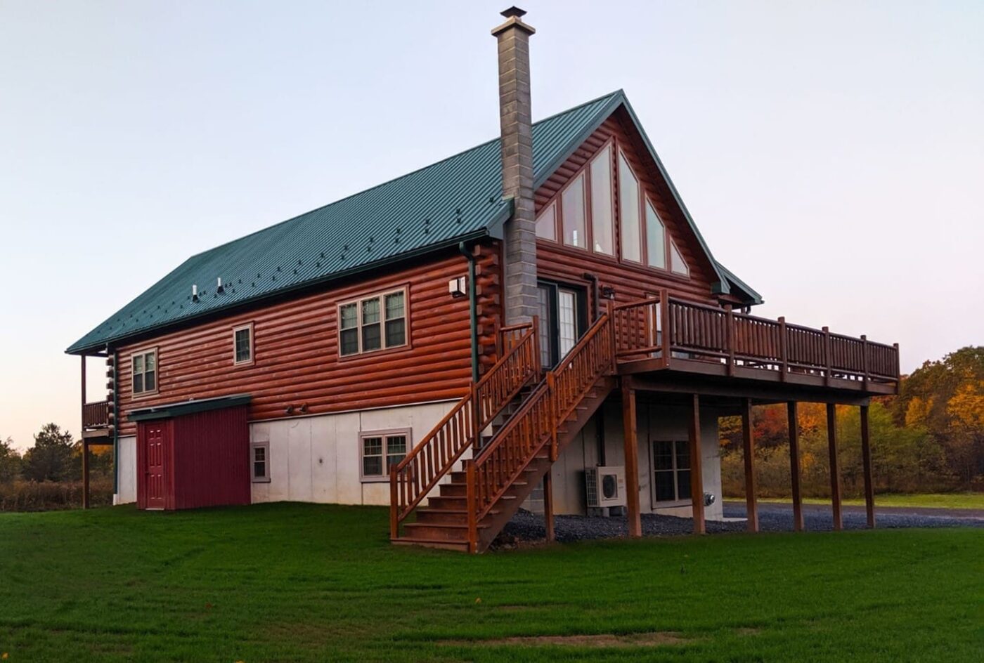 Chalet-style log cabin in New Hampshire with green roof and tall chimney.