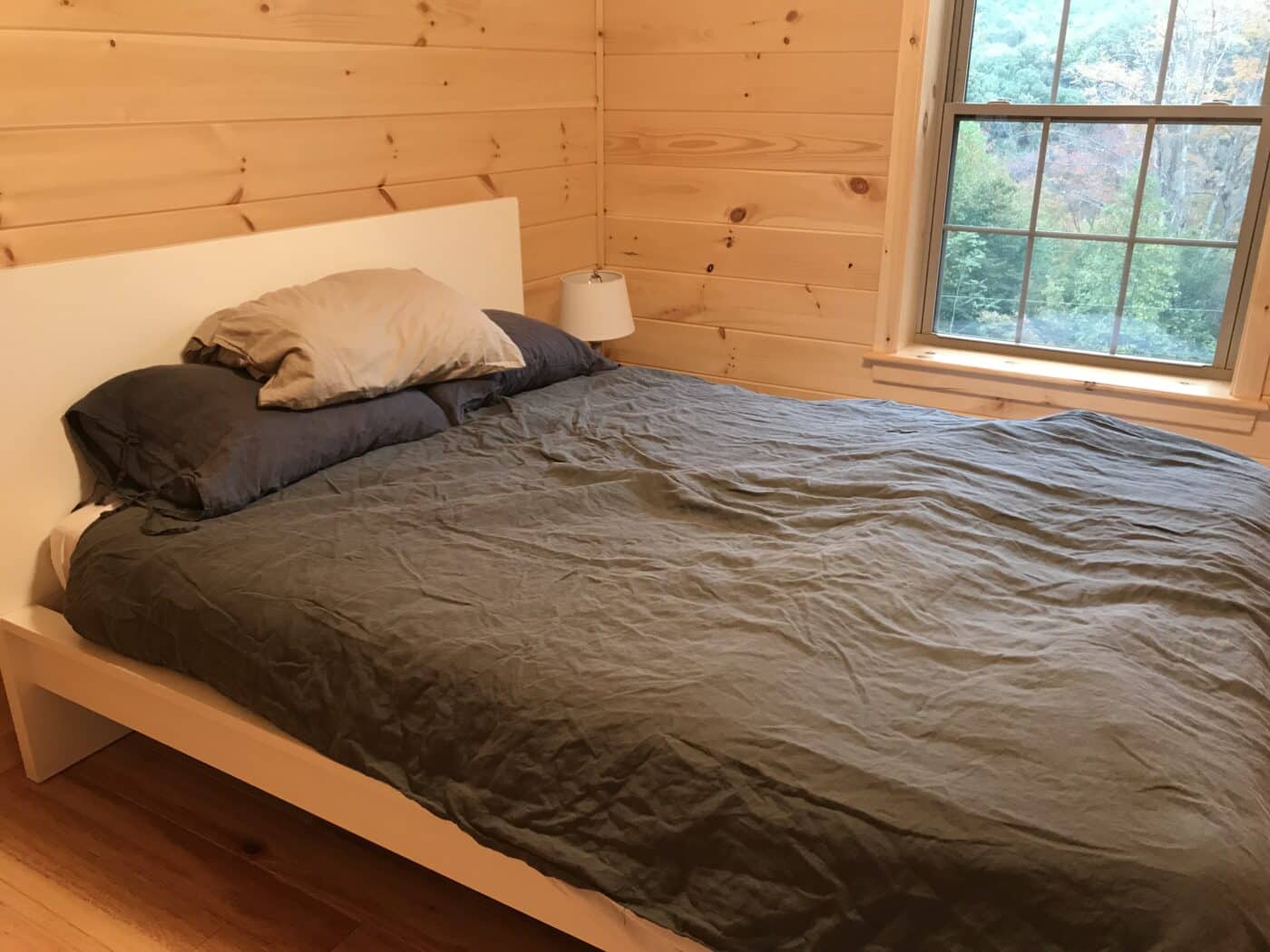master bedroom surrounded by gorgeous wooden walls inside of a prefab log cabin