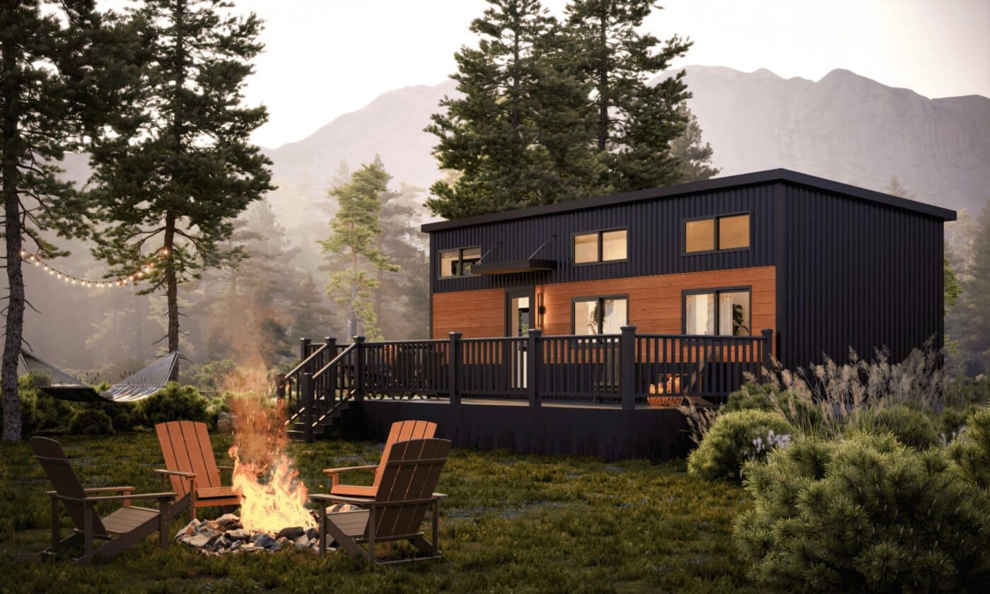Cascade park model tiny home with dark siding, large windows, and a front deck surrounded by trees.