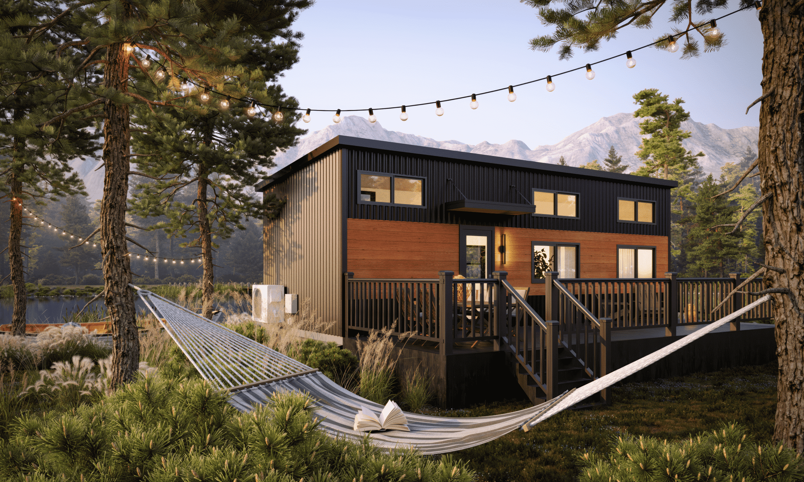Exterior view of a modern park model home surrounded by lush greenery and trees, featuring string lights, a spacious deck with railings, and a hammock stretched between two trees overlooking a serene natural setting