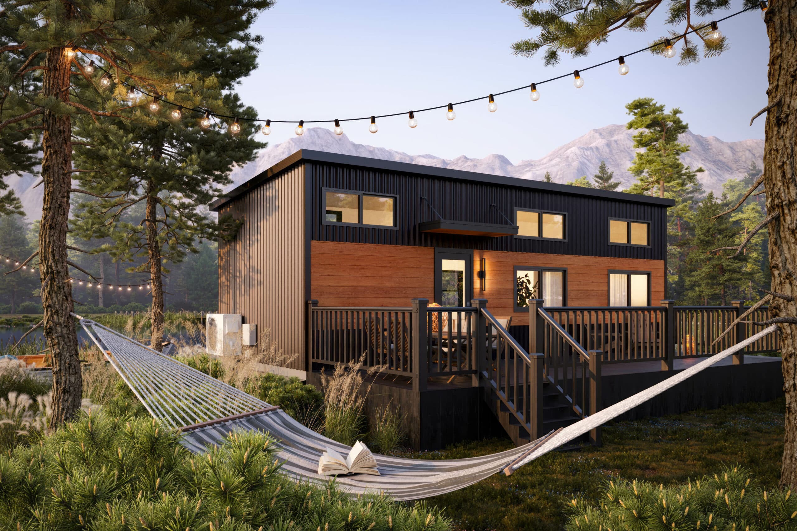 Modern tiny home with a black and wood exterior, a large deck, string lights, and a hammock in a scenic mountain setting surrounded by pine trees