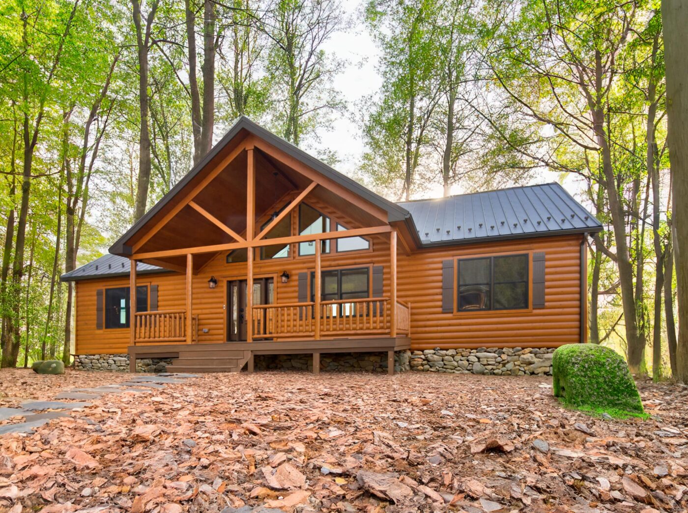 Alpine log cabin with a covered front porch set among tall trees in Kentucky.