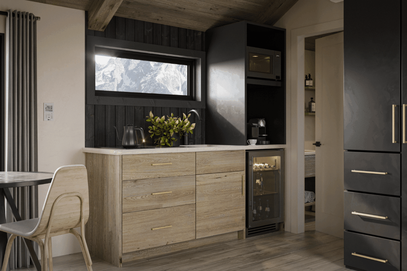 Compact kitchenette in a Denali park model with wood cabinets, black accents, and a window view of snowy mountains.