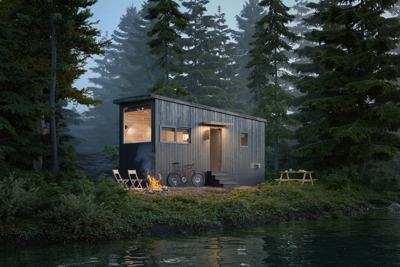 Compact Nook Studio park model tiny home nestled in a wooded setting beside a calm body of water.