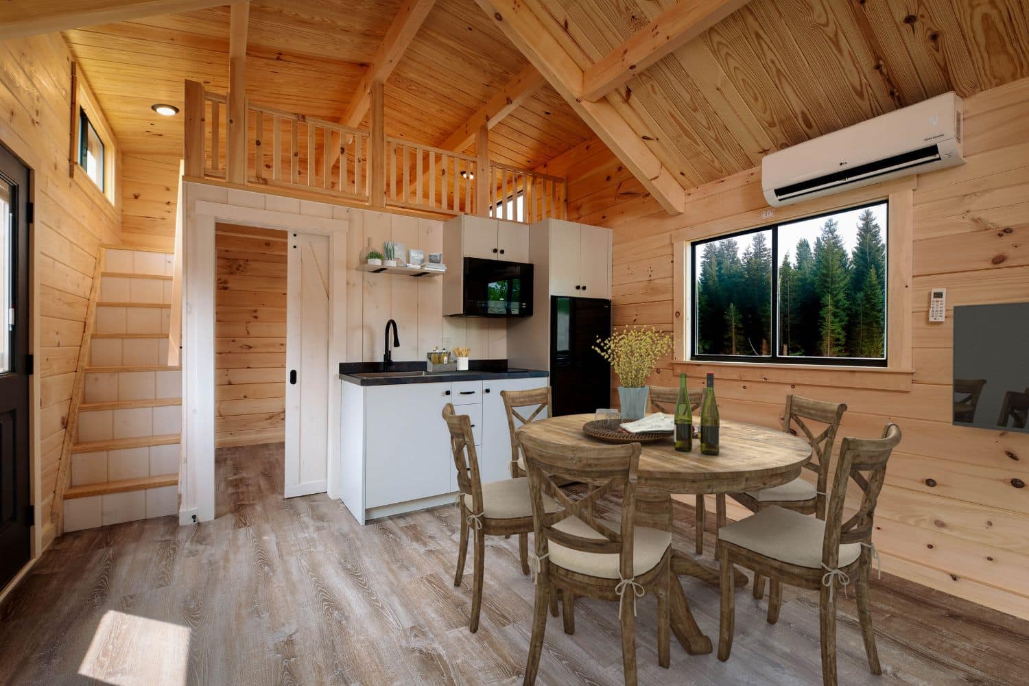 Tiny home kitchen with view of kitchen table, loft with stairs, and window looking at trees