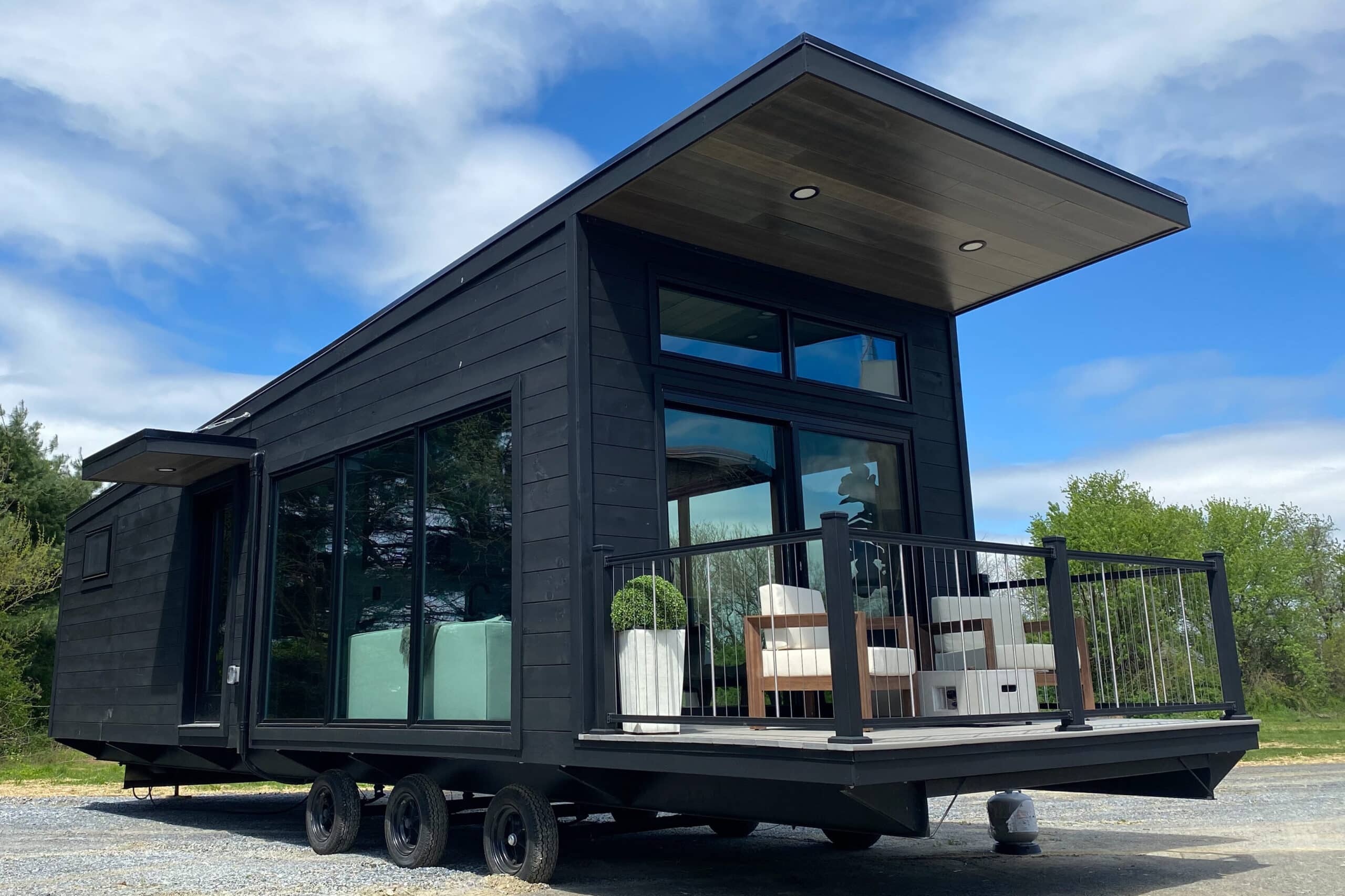 black tiny home on wheels with front porch