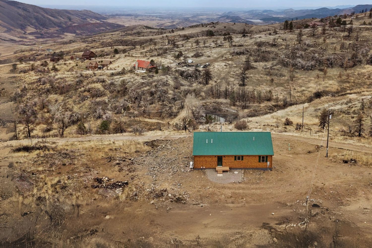 Aerial view of log cabin with green roof in vast mountain region