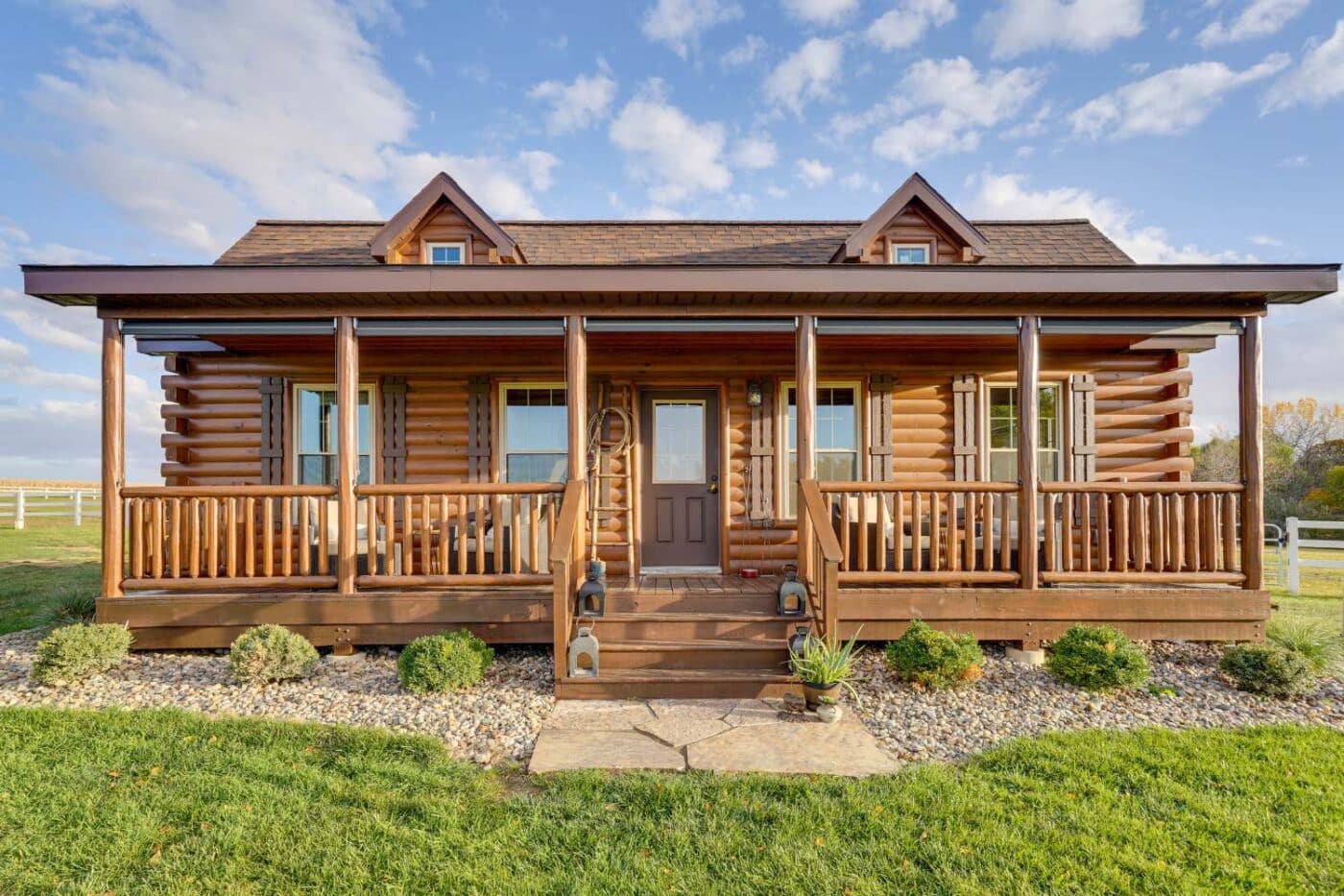 Log cabin with porch in lawn with a blue sky and stone garden