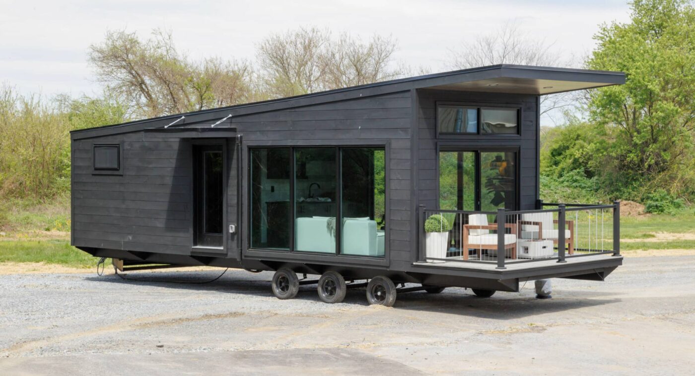 Modern Rockwood park model tiny home with dark siding, glass doors, and outdoor deck in Michigan.